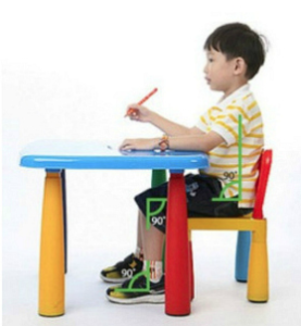 boy sitting in at his desk, his feet are on the flat on the floor, his knees and hips are at a 90 degree angle